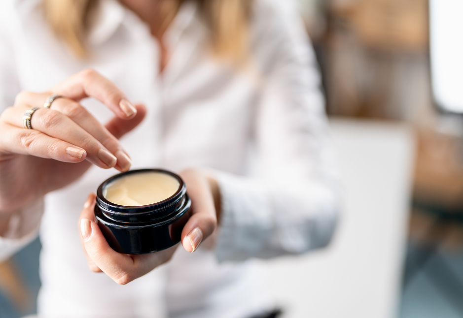 Luxury Skincare in Protective Miron Glass Packaging – Preserving Quality & Freshness Close-up of a woman using a premium skincare cream from a dark Miron glass jar, highlighting product freshness and sustainable packaging.